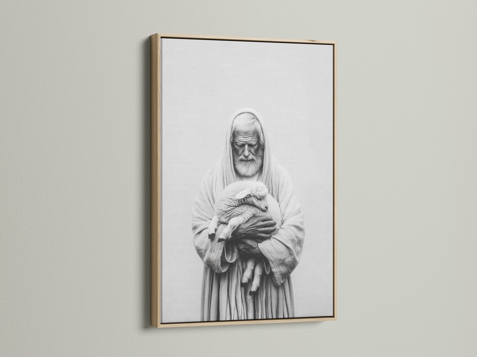 A framed artwork hangs on a light beige wall. The artwork has an oak frame. The frame is thin and modern. The art print is a black and white image of a man holding a lamb. Decorate your space with this classic artwork.