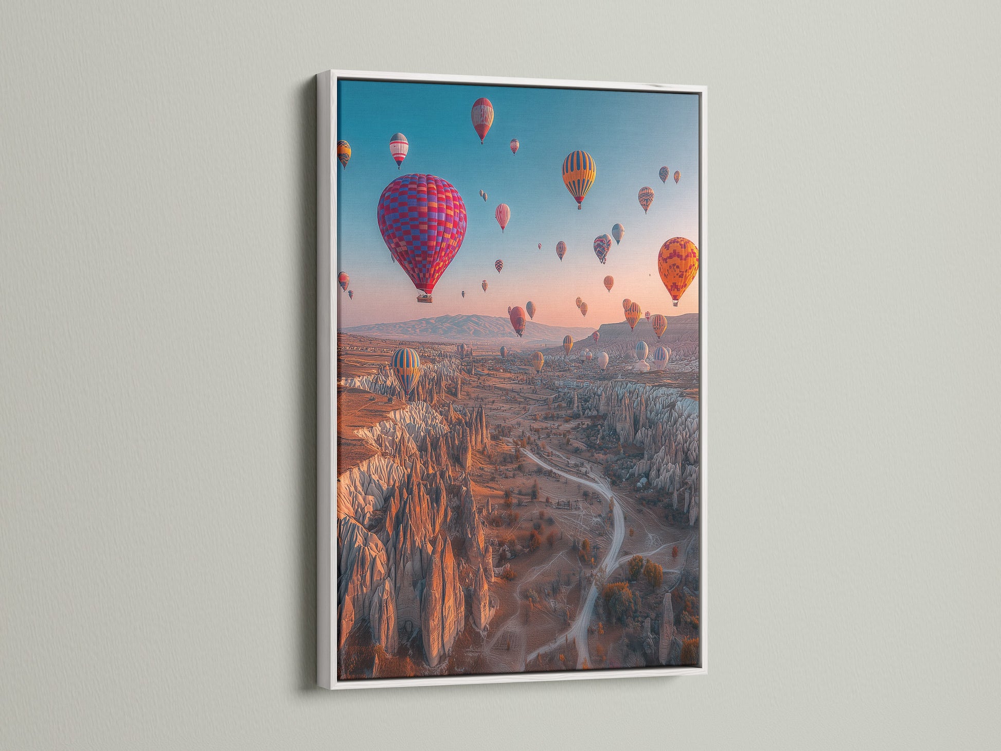 This hot air balloon art is framed in white. The white frame provides a clean modern look. It complements the colorful Cappadocia landscape. Perfect travel photography for bedroom or living room adventure decor.