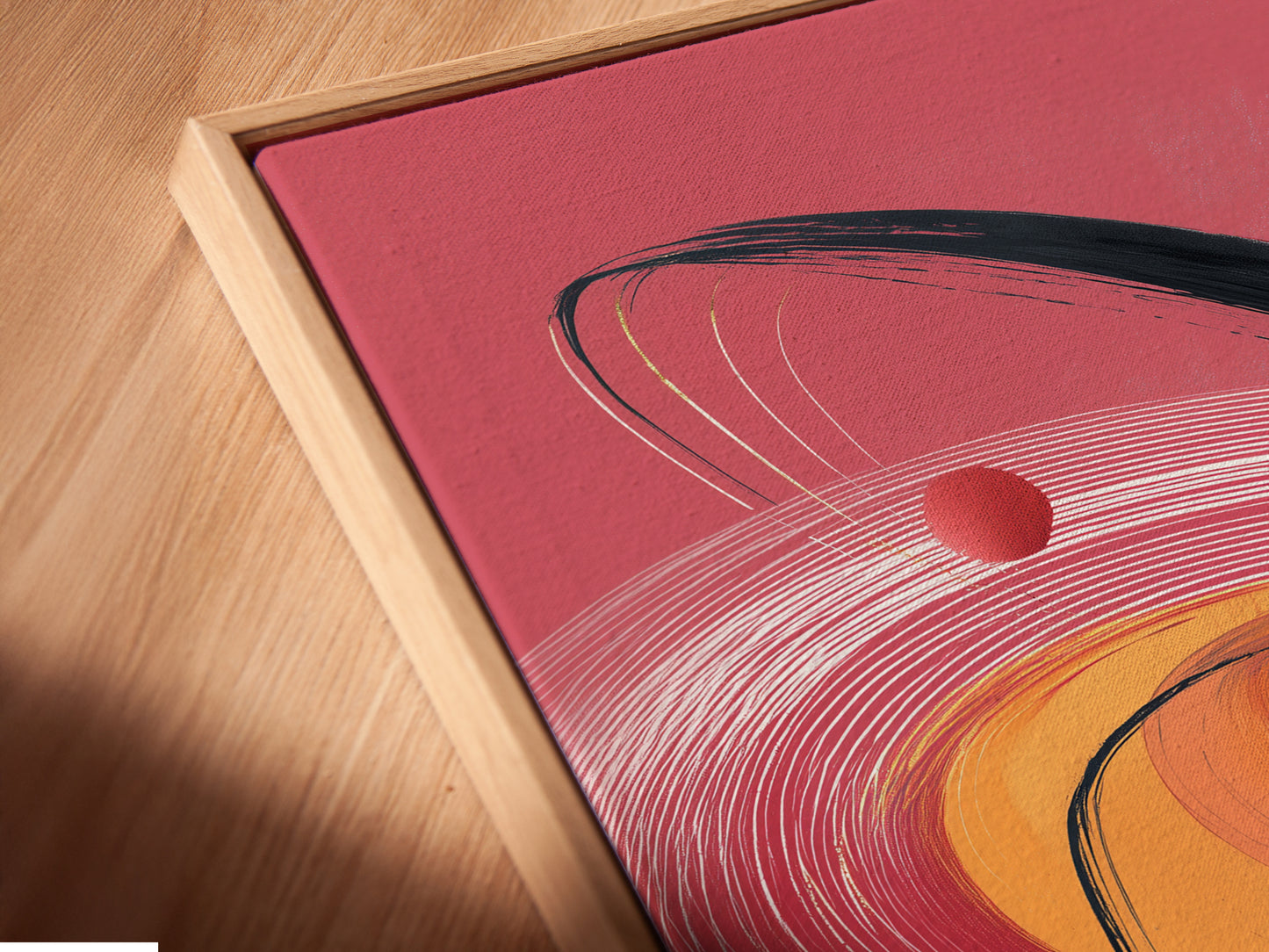 Close-up angled view of a canvas print in a floating frame. This abstract swirl art features coral pink and gold accents. Perfect for adding contemporary motion to modern spaces. Enhance your living room or bedroom.