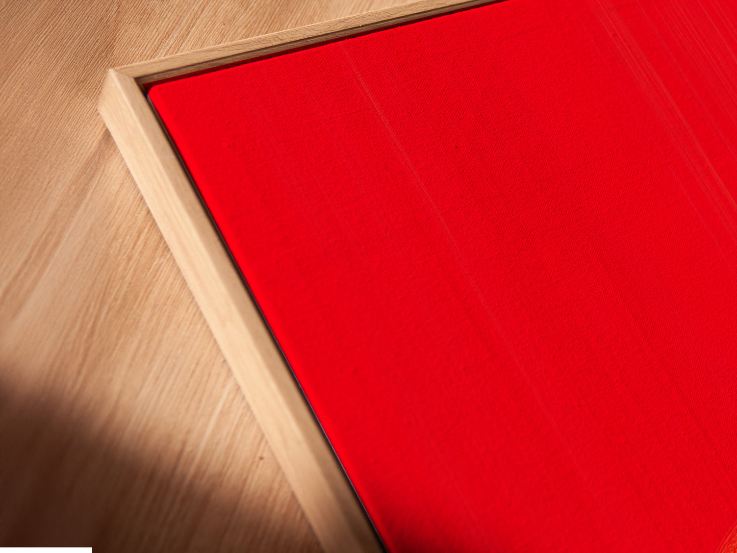 A close up of a Cowboy Sunset Canvas Print in a floating frame. The red orange silhouette pops against the light wall. This western artwork is perfect for rustic themed spaces. Enhance your home decor with this unique piece.