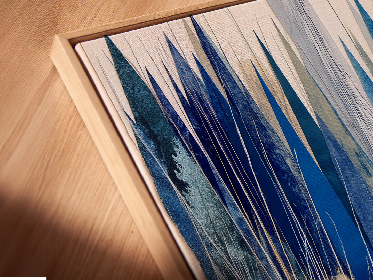 A close-up angled view reveals the exquisite detail of a canvas print in a floating frame. The winter cabin artwork features a snowy lake. The floating frame enhances the blue and white abstract winter art. This modern wall art provides a sleek nature print option. Ideal for chalet decor and cozy cafรฉs.
