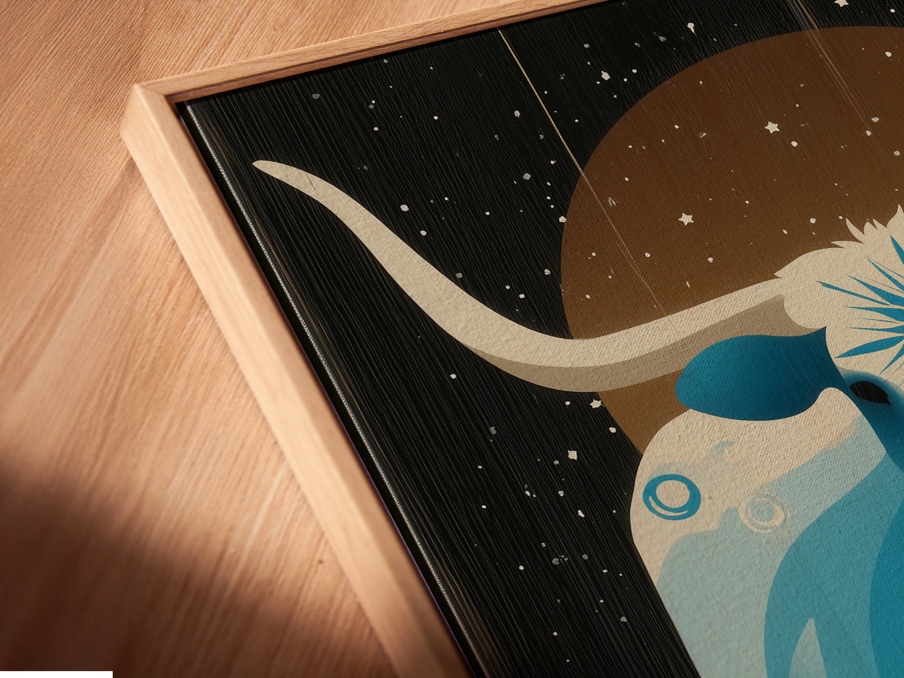 Angled close up of the Celestial Bull canvas print. This artwork is displayed in a floating frame. The blue and beige tones complement each other. This is a great example of Western Zodiac wall art. Perfect for a cozy bedroom.