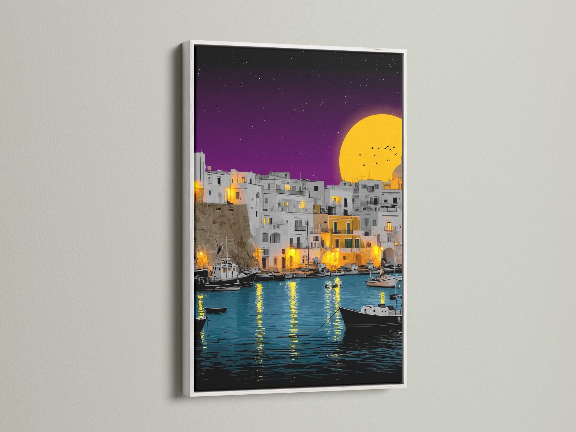 A white frame elegantly displays the coastal village artwork. The art captures a peaceful Mediterranean harbor. The scene is illuminated by a setting sun. This artwork is perfect for adding a serene waterfront decor element to your home or office.