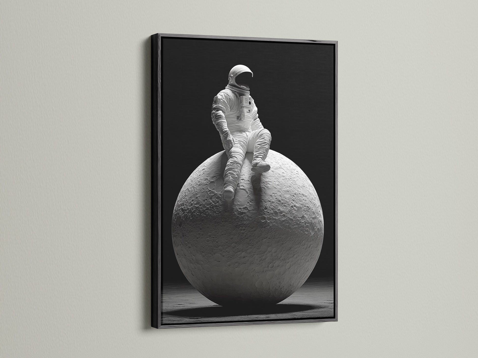 A dramatic art print features an astronaut sitting on the moon. The artwork is framed in a sleek black frame. The black frame adds contrast and sophistication. It enhances the overall impact of the artwork in the space.