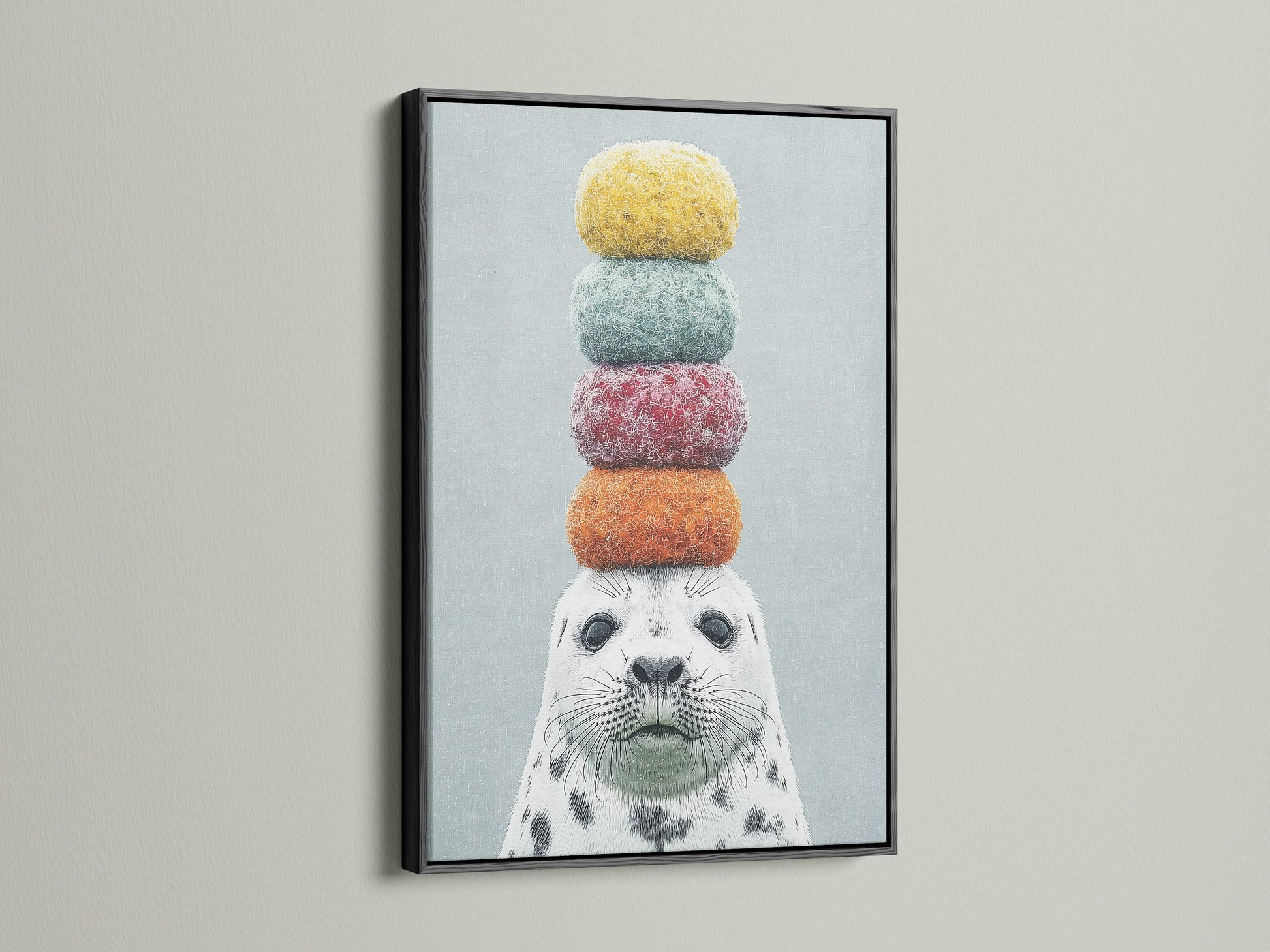 Framed whimsical seal artwork with colorful macarons on its head. The art is presented in a modern black frame. A fun and quirky addition to any space. This animal canvas art is ideal for kids rooms or coastal themed decor. Explore our playful art print collection.