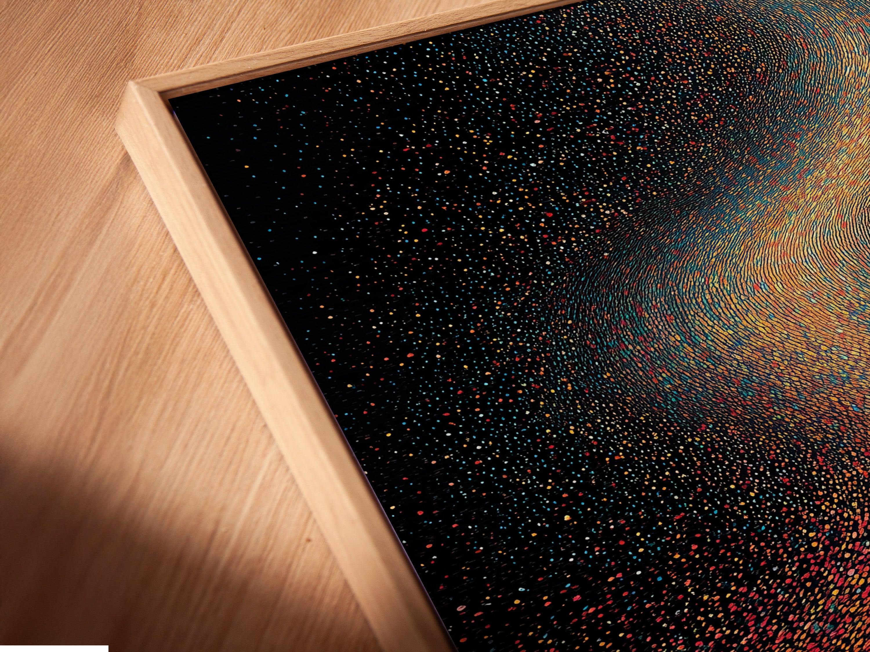 An angled close-up reveals the beauty of a canvas print. It is set in a floating frame. The artwork features a cosmic galaxy theme. It showcases surreal space wall art. The floating frame enhances the celestial pointillism. This piece is ideal for contemporary interiors.