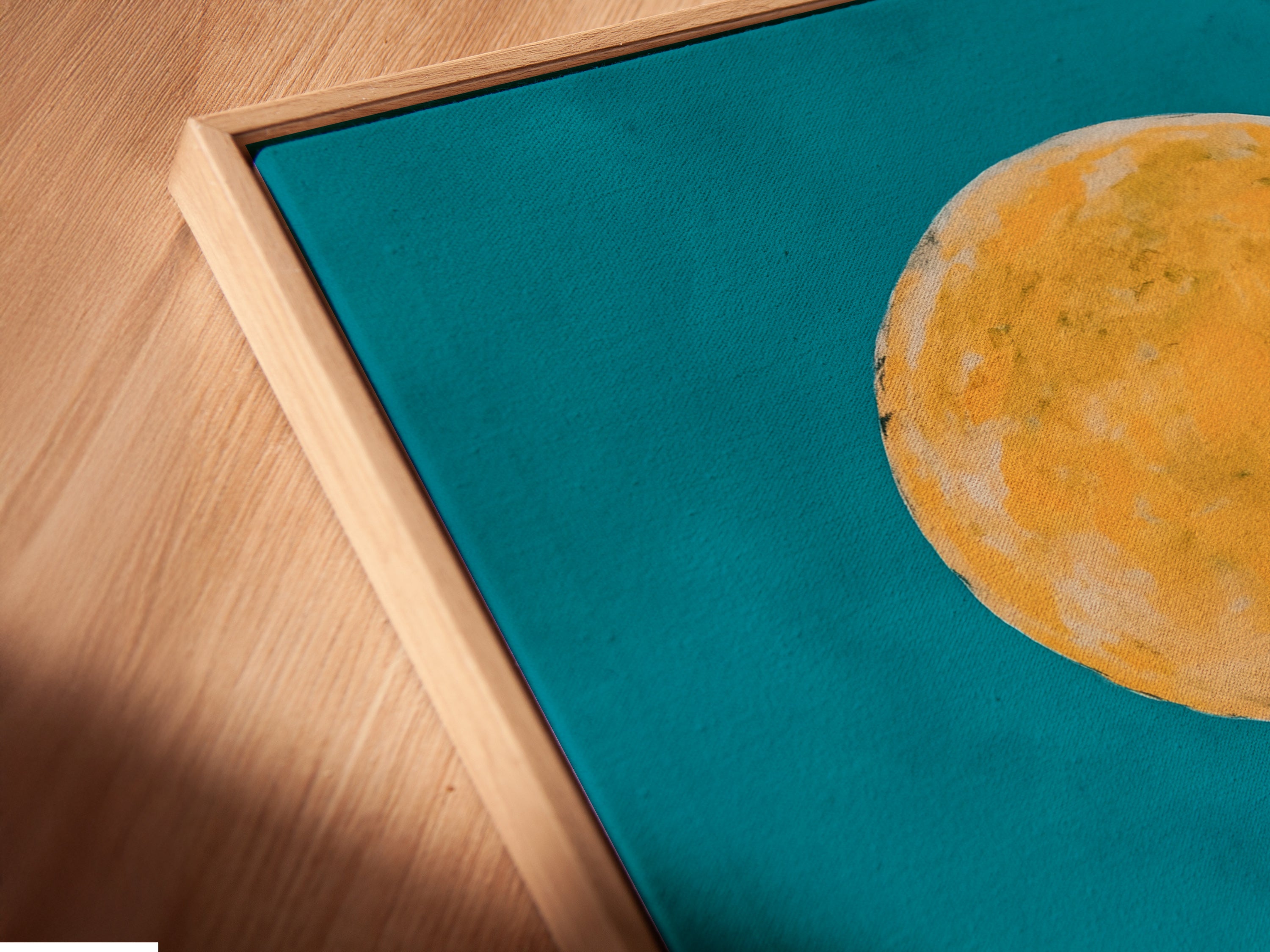 A close-up angled view reveals a canvas print in a floating frame. The Wolf Moon artwork is beautifully showcased. The teal and orange colors create a captivating scene. This southwestern desert wall art enhances any interior. It is a modern and stylish piece.