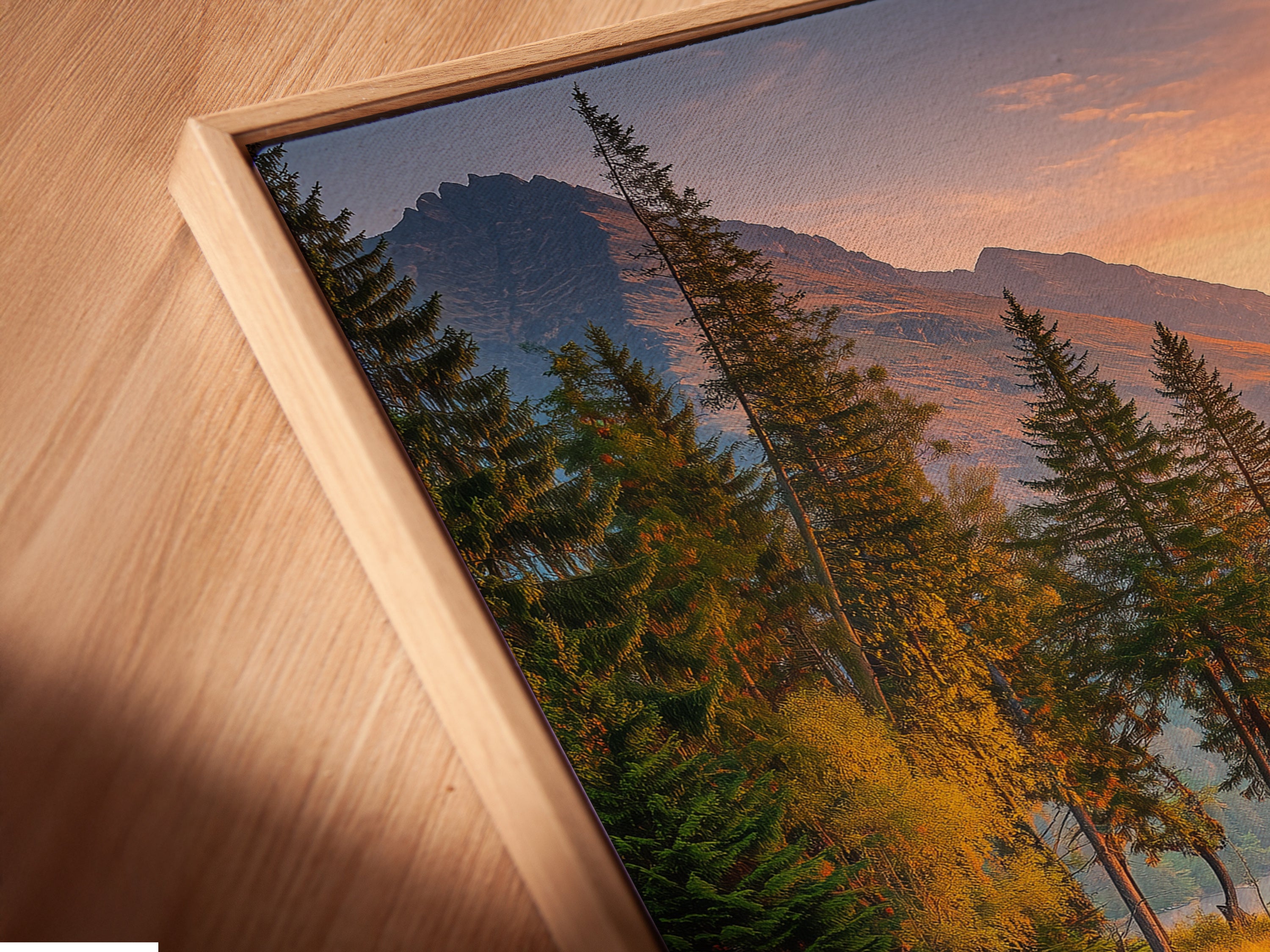 A close-up of a canvas print in a floating frame. The mountain lake art features a sunset reflection. The fine art print is perfect for cabin decor and rustic interiors. It's an elegant way to bring nature into your home. The floating frame adds a contemporary touch to the classic landscape.