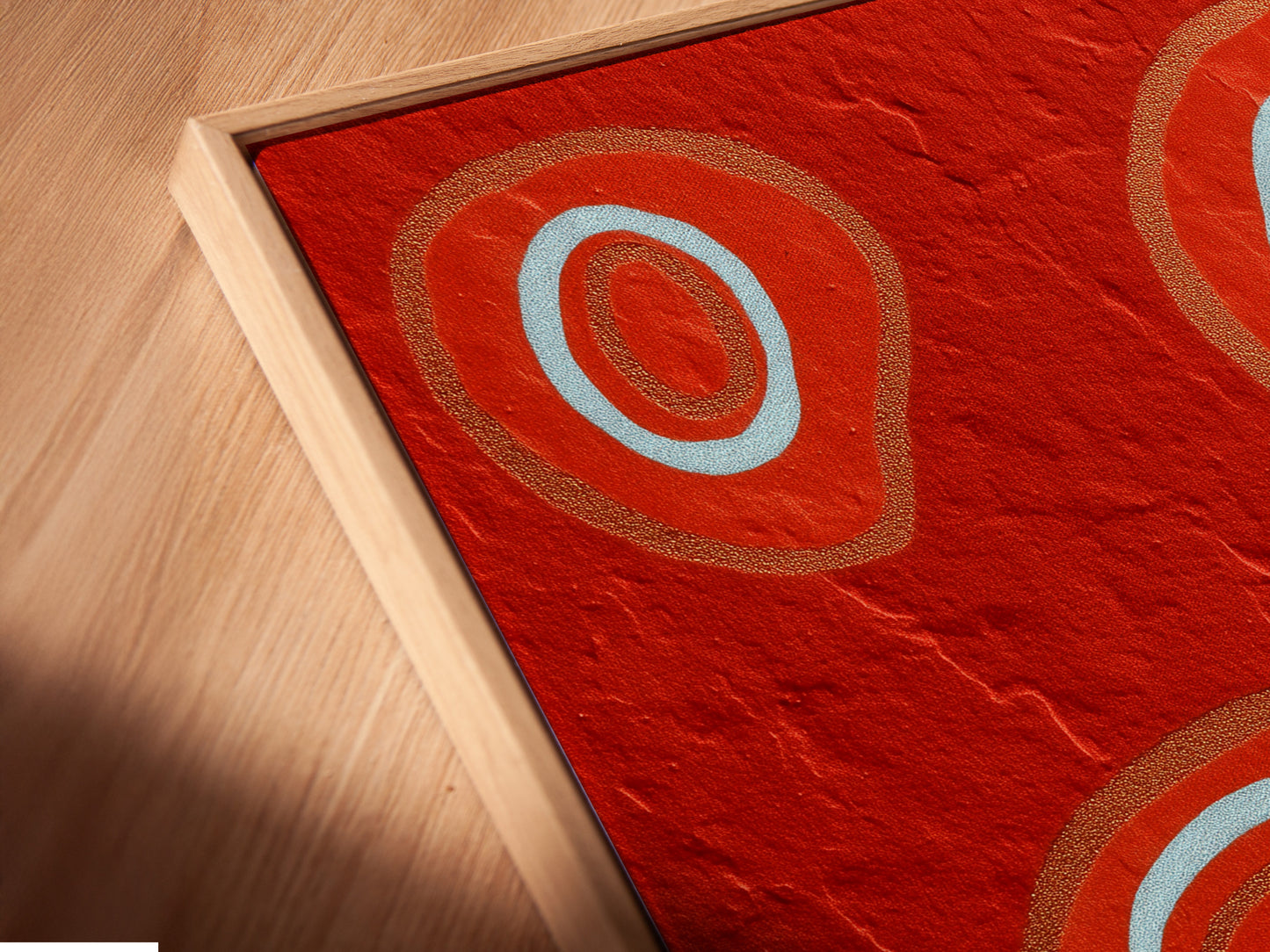 A close-up angled view reveals a canvas print in a floating frame. The abstract red art features bold geometric patterns. This modern wall art enhances any contemporary space. The floating frame adds a unique touch. It creates a visually stunning display. Perfect for modern artwork lovers.