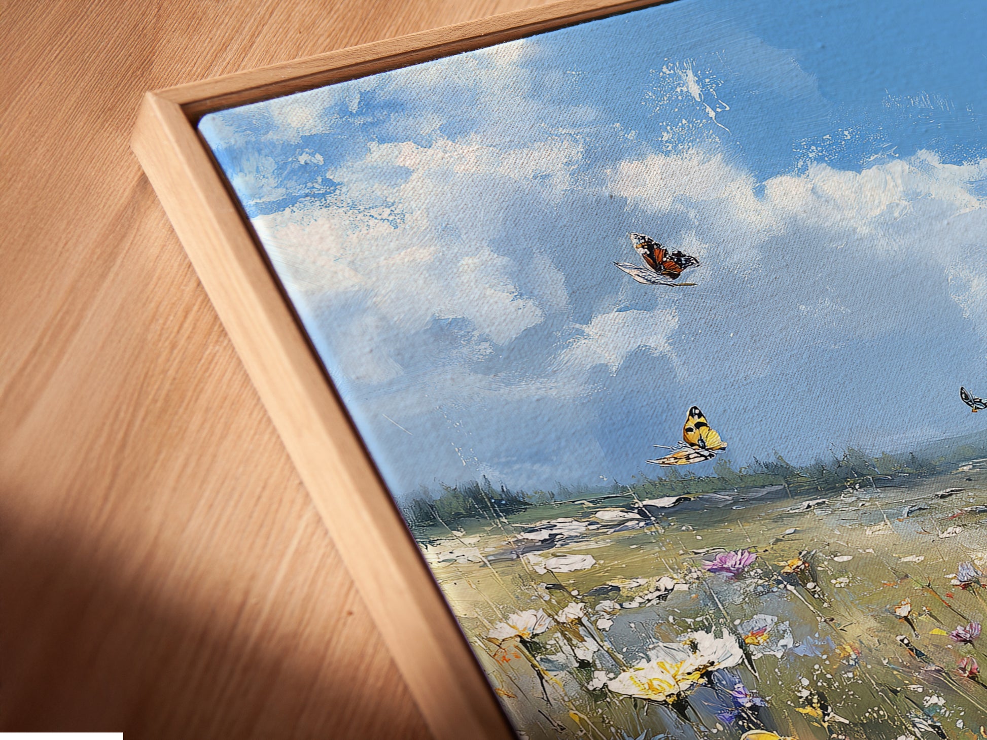A close-up shot of the Wildflower Meadow canvas print. It features a floating frame that adds depth. The artwork shows a beautiful butterfly field. The art brings a blue sky landscape painting to any room.