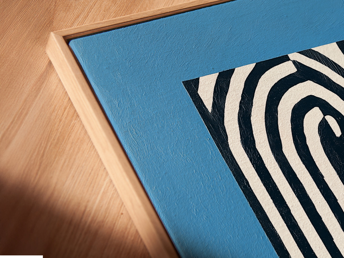 Close-up of a canvas print in a floating frame. The abstract lines and blue backdrop create a modern look. This minimalist artwork enhances any room. Perfect for contemporary decor. See the details of our framed canvas prints now.