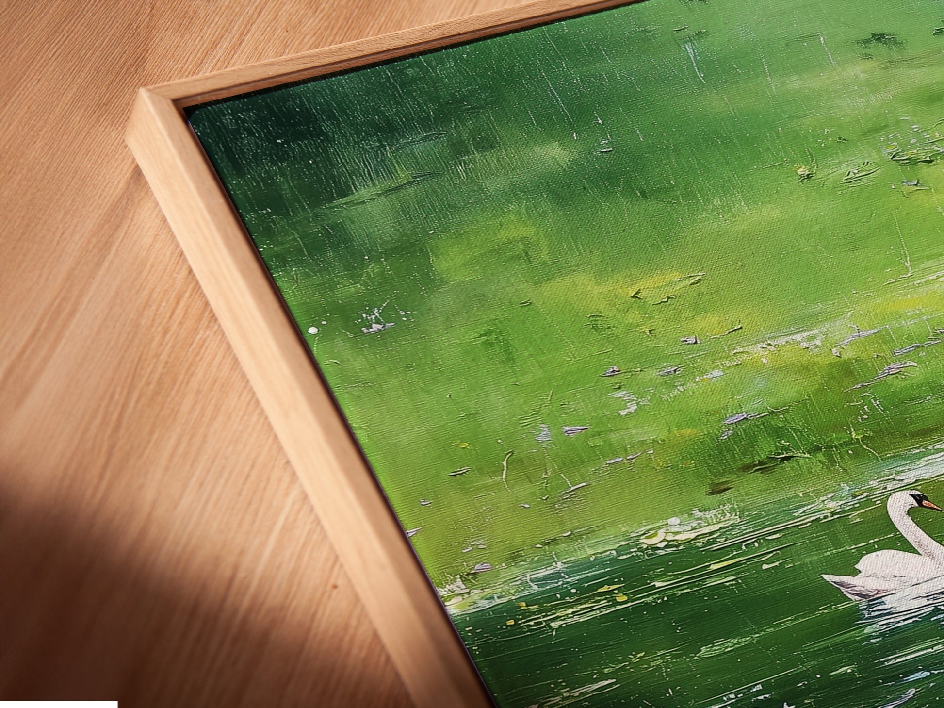 Close-up angled view of a canvas print in a floating frame. The artwork features a swan on a pond. The floating frame gives a modern and gallery-like feel. The canvas print adds texture. It brings depth to the artwork presentation.