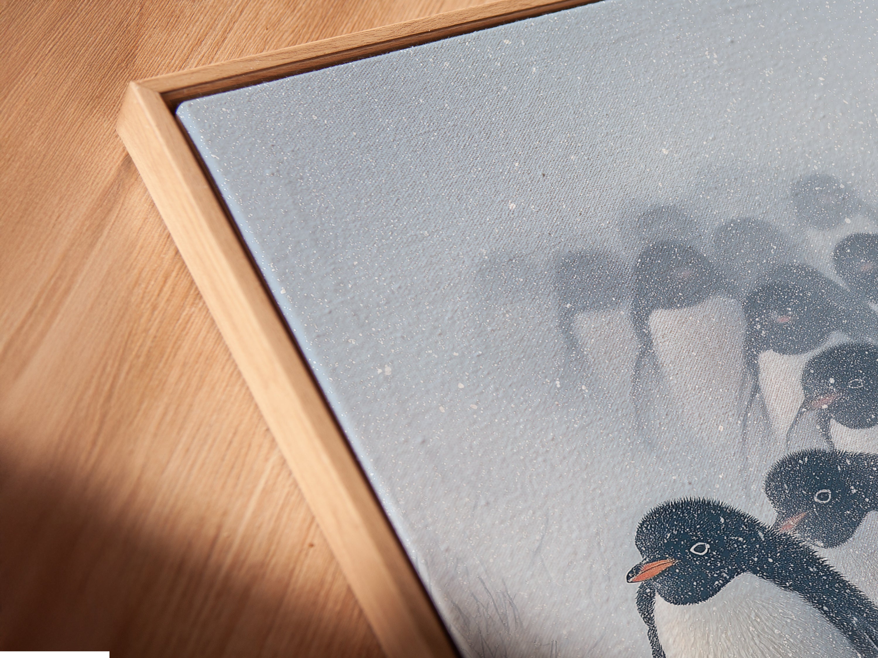 A close-up of a canvas print in a floating frame showcasing penguin artwork. Perfect for adding a modern touch to any space. The floating frame enhances the artwork making it a focal point. This is ideal for coastal or minimalist interiors.