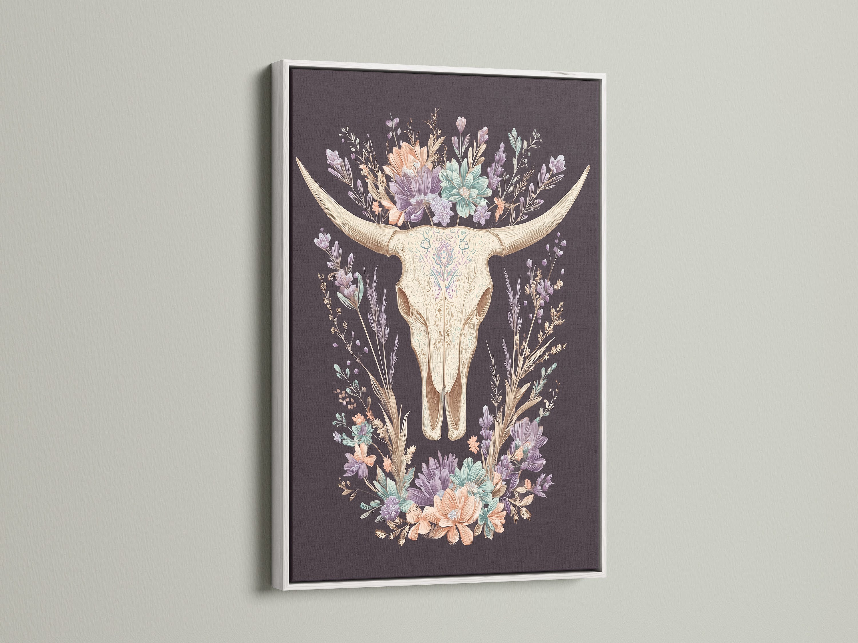 Artwork featuring a bovine skull with floral elements. It is encased in a white frame. The white frame offers a clean and modern aesthetic. It allows the artwork to stand out. The art piece is perfect for light-colored walls. Consider this art piece for a sophisticated look.