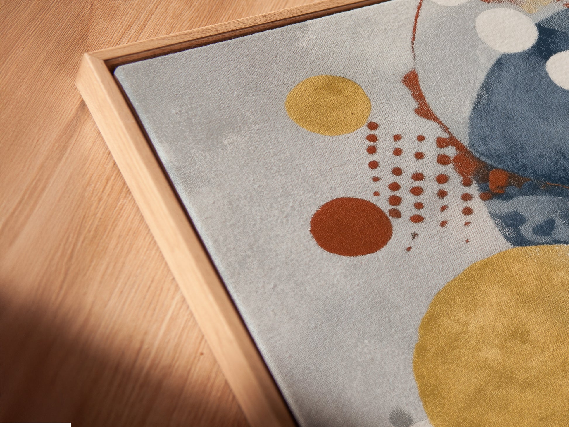 A close-up angled view shows a canvas print in a floating frame. The abstract artwork features blue and gold circles. This modern piece is perfect for adding style to your home or office.
