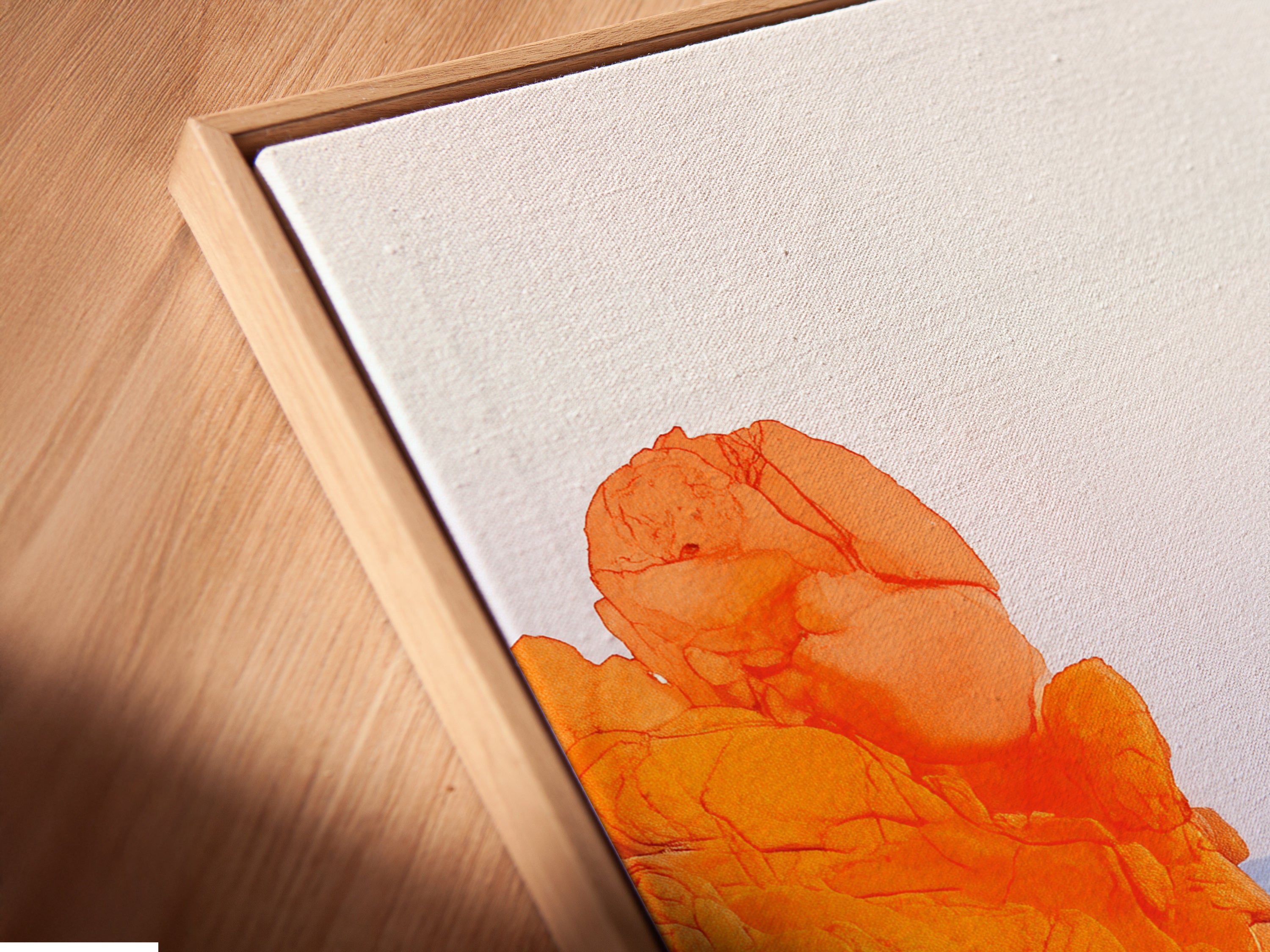 Angled close up of a canvas print in floating frame. The coastal art is orange and blue. Perfect for modern decor. The floating frame gives the artwork a contemporary look. It makes the colors pop. Perfect for living rooms and bedrooms.