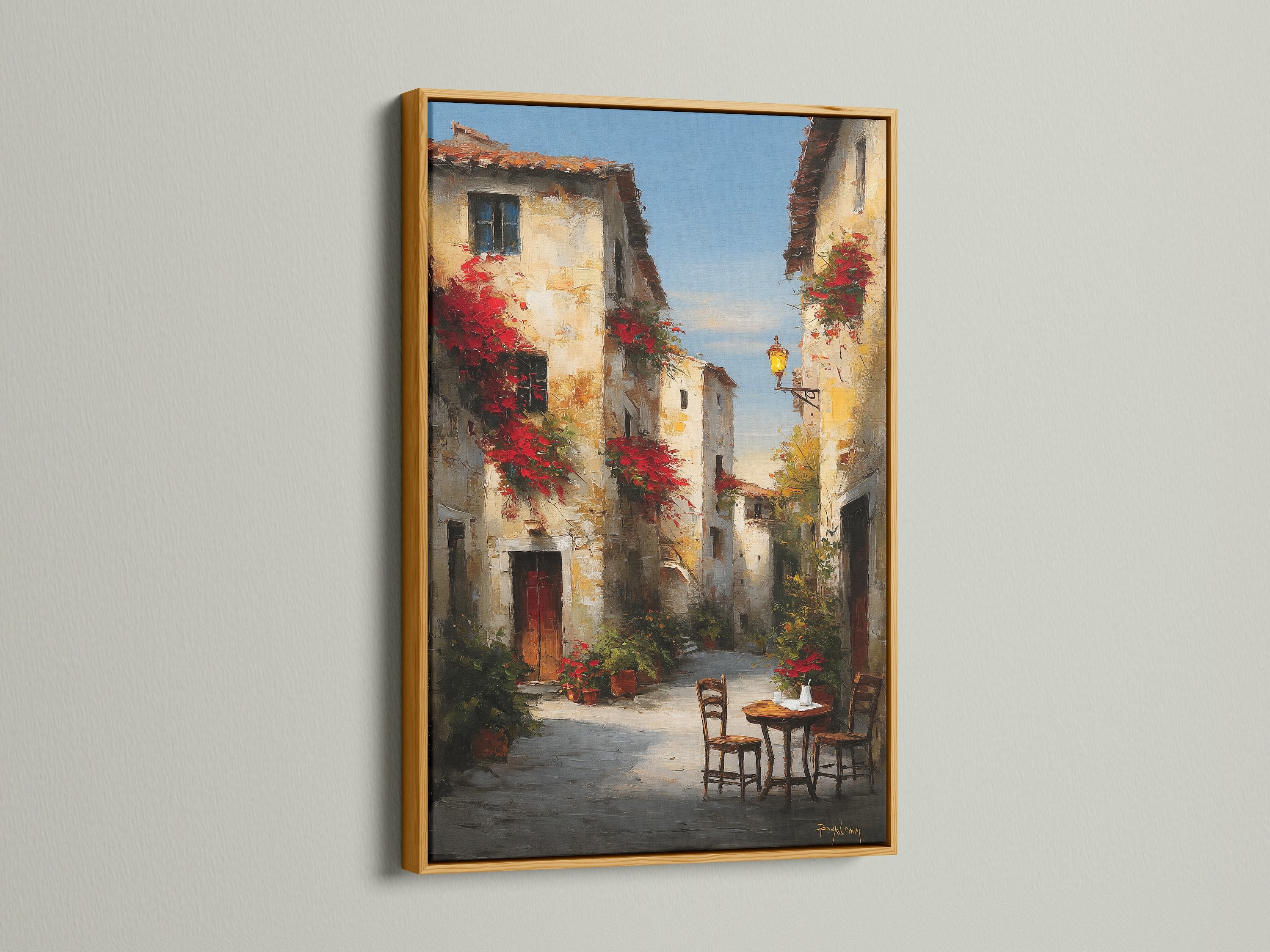 Gold frame highlighting a gorgeous street artwork. The artwork depicts a delightful European street. Red flowers bring life to the buildings. A cozy table and chairs offer a place to pause. The gold frame adds a touch of luxury. Transform your space with exquisite artwork.