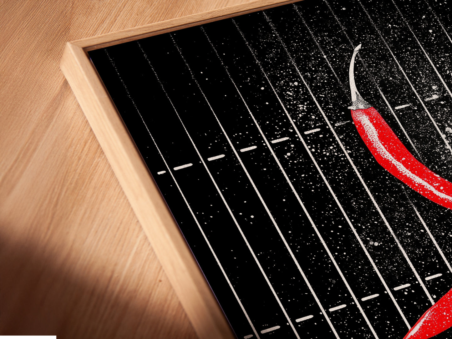 Close-up angled view of a canvas print in a floating frame. The chili pepper artwork is elevated. The floating frame adds depth. This modern art is perfect for any space. Ideal for homeowners and interior designers.