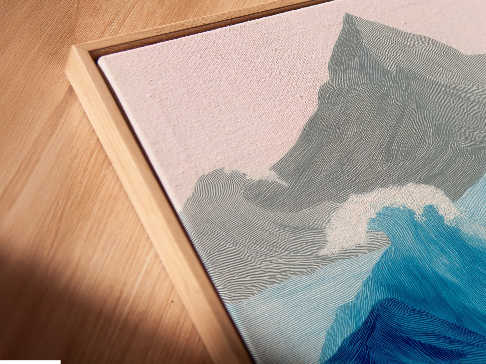 This is a close up of a canvas print in a floating frame. The floating frame gives the artwork a unique look. The canvas print is high quality and detailed. The art features abstract ocean waves and mountains. The piece adds dimension to the wall. It is perfect for creating a gallery like display. It is a modern and stylish art choice