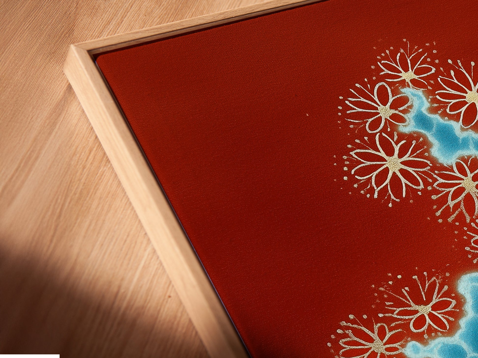 A close-up angled view of a canvas print featuring abstract river art. The artwork is showcased in a floating frame. The terracotta and blue color palette creates a modern botanical art piece. Enhance your space with this unique water flow print.