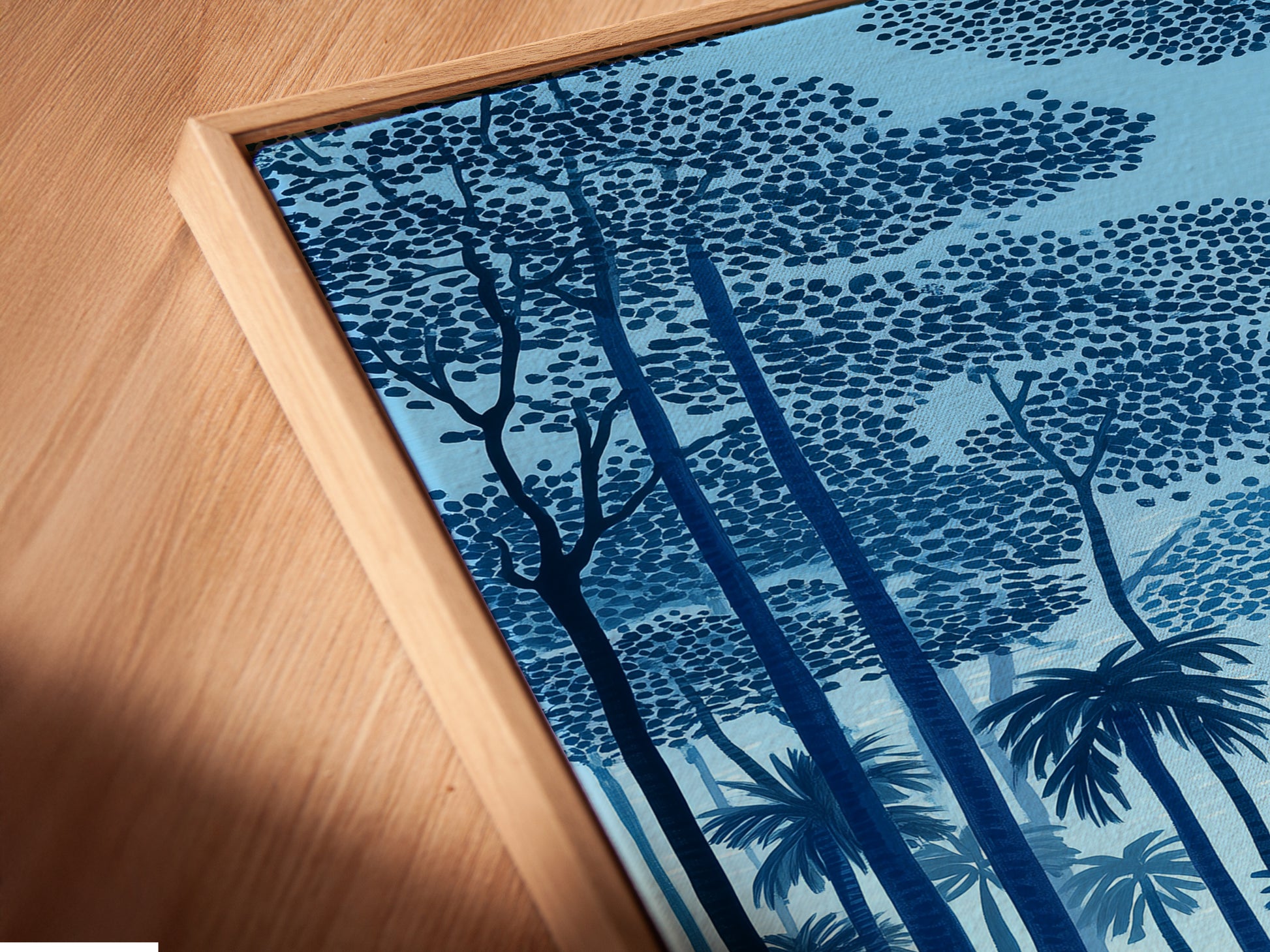 A close-up angled view of a canvas print in a floating frame. The tropical beach artwork brings a coastal seascape to your home. Notice the fine details of the indigo blue sunset and palm tree art. This piece is perfect for adding a touch of island art to any space.