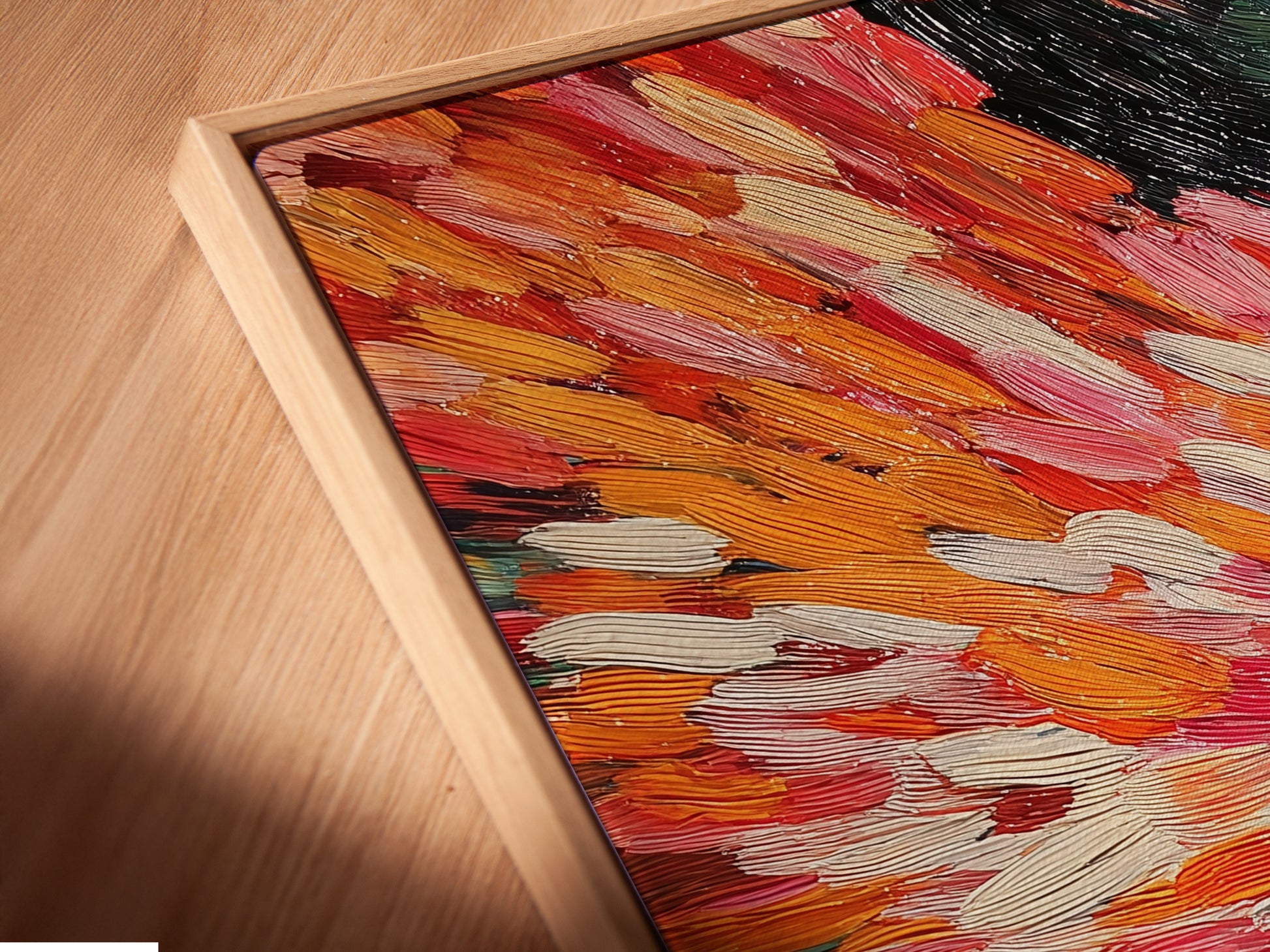 A close up angled view shows a canvas print in a floating frame. The abstract burst artwork features dynamic brushstrokes. Red and orange hues create a vibrant piece. This modern art is perfect for contemporary spaces. Add this energetic painting to your collection.