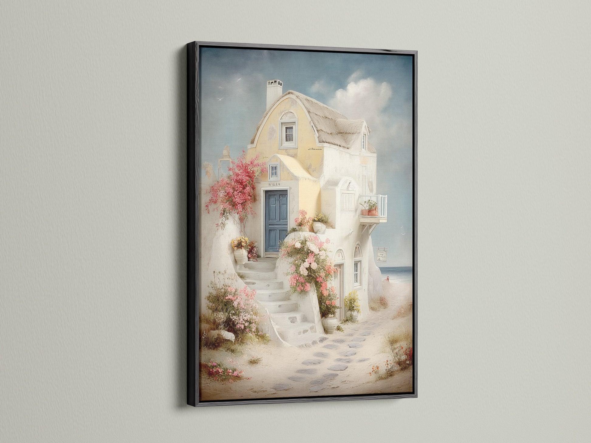Coastal artwork in a black frame. The artwork features a Mediterranean house canvas with a blue door and floral stairway. Perfect for adding Greek island art to your vacation home decor. This sea view print enhances any space. Ideal for living room wall art.