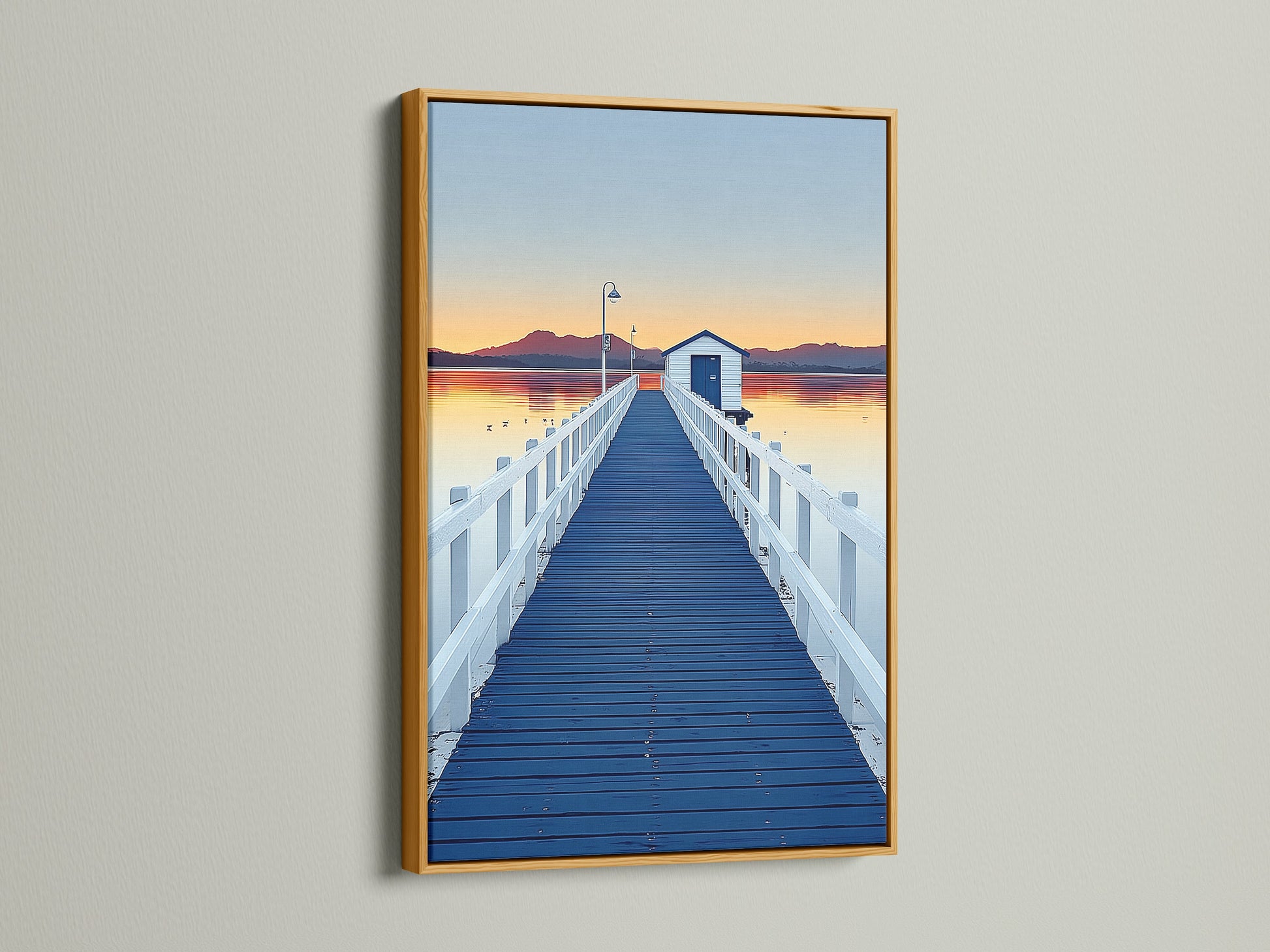 Elevate your space with dock sunset artwork. See a blue pier wall art print in a gold frame. The frame enhances the coastal scenery photography. Bring a touch of nature to your home decor with this piece.