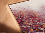 An angled close-up reveals the texture of a canvas print. The canvas print is set in a floating frame. The floral meadow artwork is vibrant with red and white wildflowers. This creates a stunning visual effect. Perfect for adding depth to your art collection.
