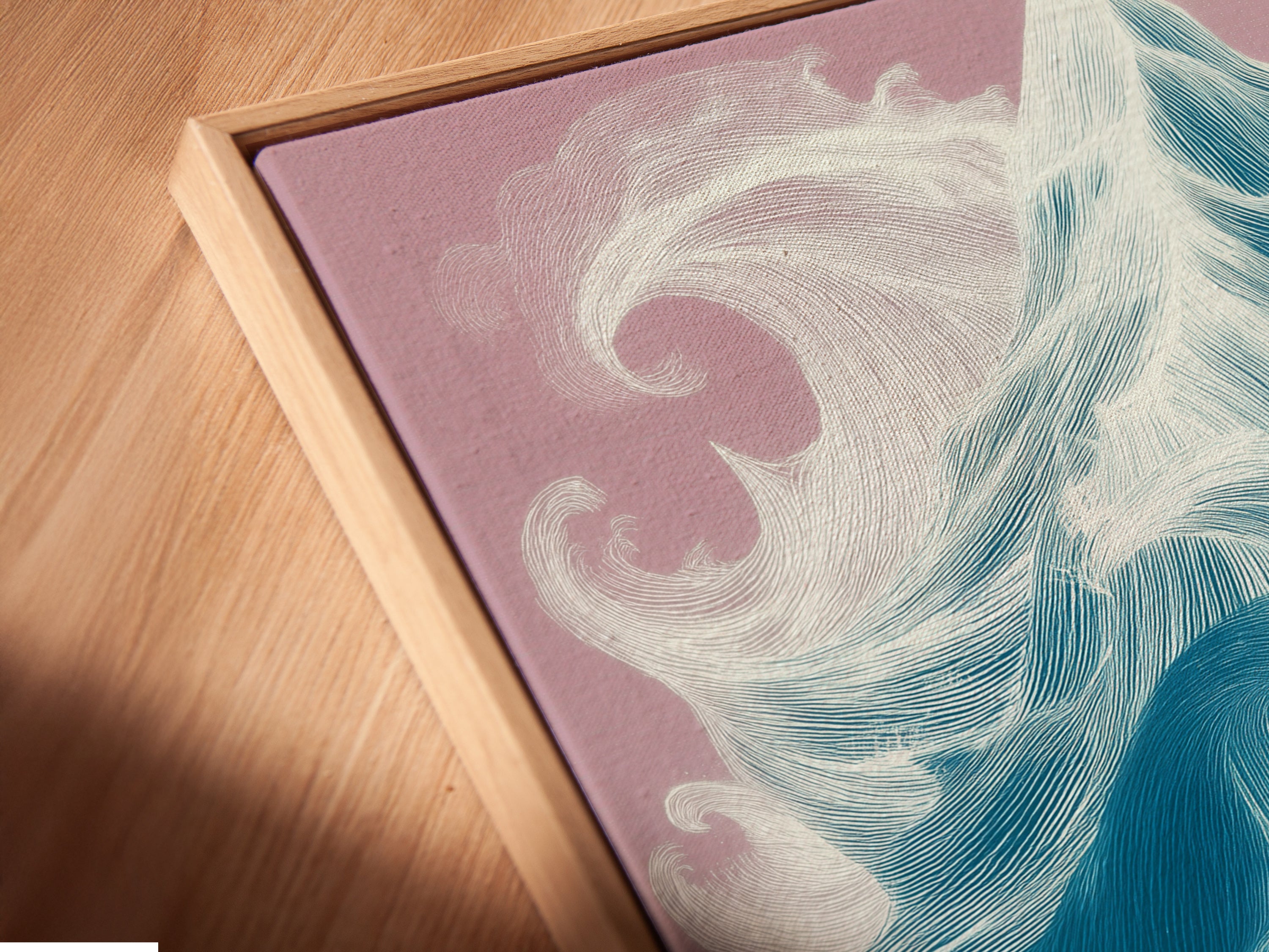 Angled close up of a ocean wave canvas print in a floating frame. This modern coastal art piece is perfect for creating a relaxing atmosphere. Its clean lines and vibrant colors make it a standout addition.