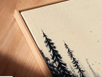 A close up angled view of a canvas print in a floating frame. The forest artwork features a monochrome forest scene. Notice how the frame enhances the misty woodland wall art. Perfect as nature artwork for a bedroom or living room. This minimalist art complements a Scandinavian interior.