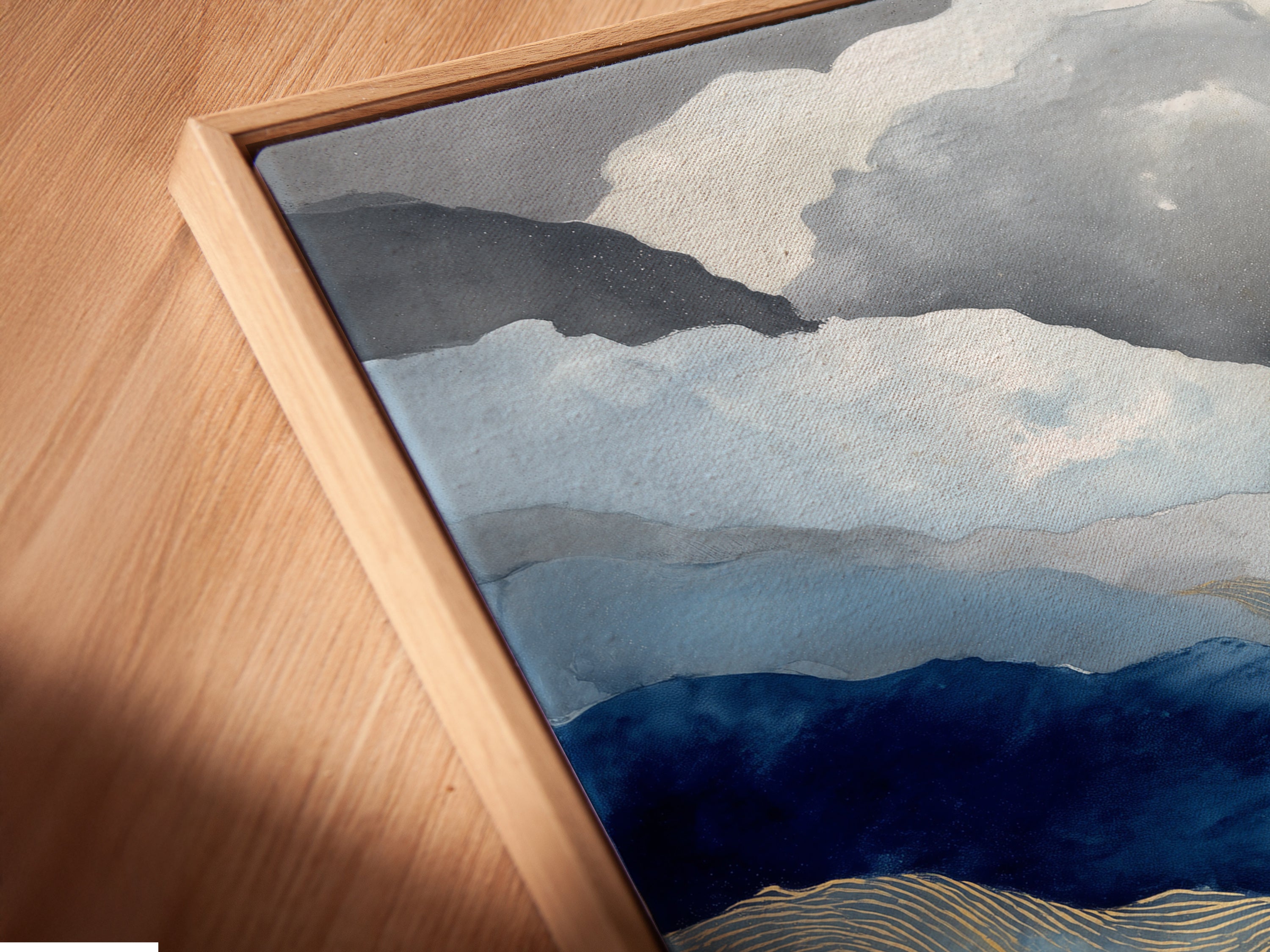 Angled close-up of a canvas print in a floating frame. The abstract mountain artwork showcases blue and gold colors. Modern nature art for office wall decor. Contemporary artwork for any room.