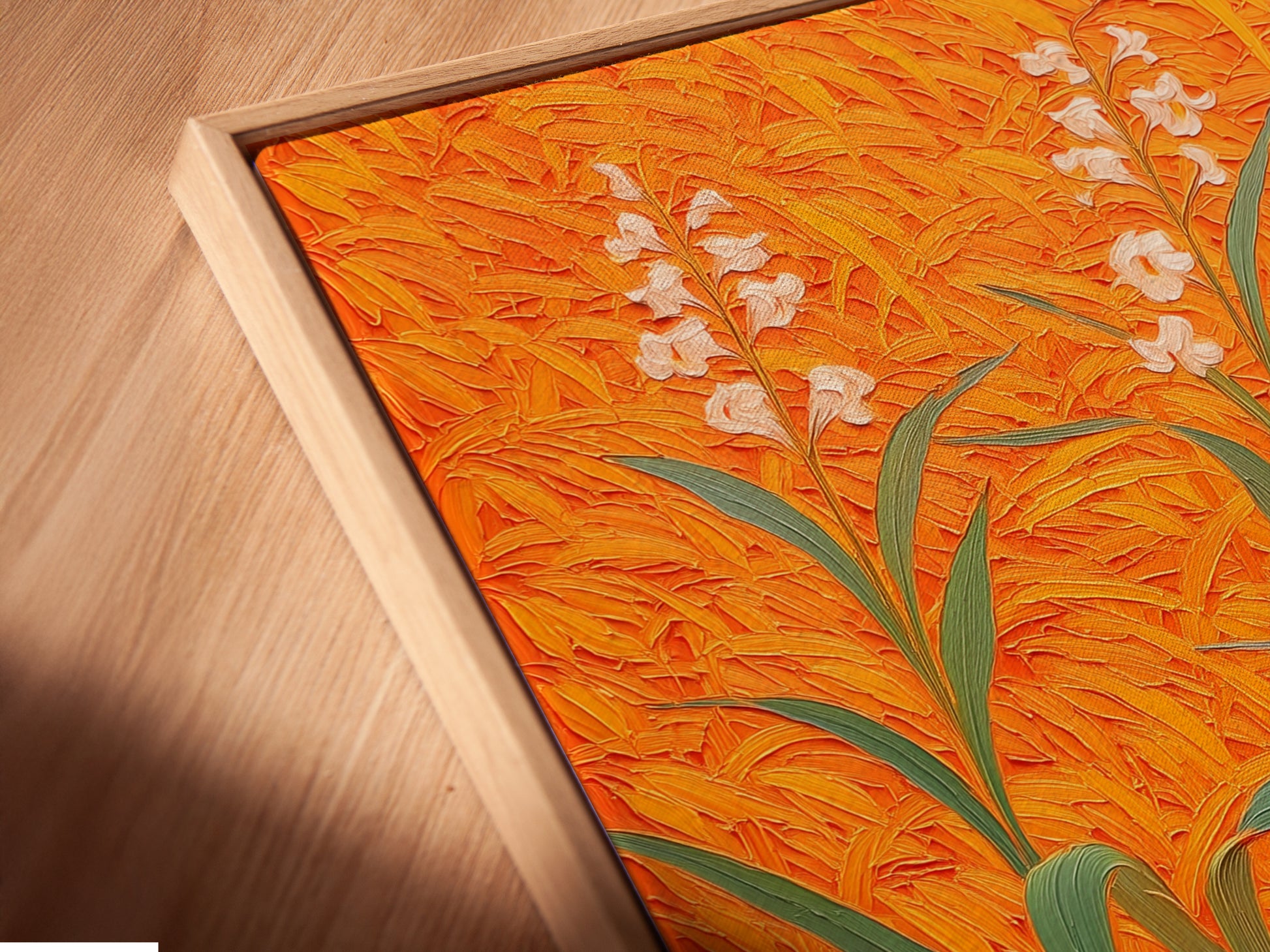 A close-up angled view of a canvas print in a floating frame. The artwork features a floral field with an orange botanical theme. This modern plant artwork is ideal for entryway wall decor. The floating frame adds a contemporary touch. Perfect for living rooms bedrooms and offices.