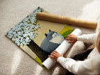 A woman is carefully rolling a fine art poster paper featuring a cat under a tree. This showcases the care in handling the animal canvas print. The spring blossom artwork adds a touch of nature to any space. Perfect for cat lovers seeking unique wall art.