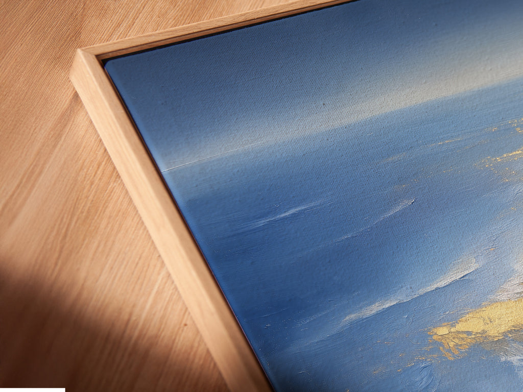 A close-up shows the Ocean Reflection canvas print in a floating frame. The angled view highlights the texture and details of the blue and gold abstract artwork. This coastal wall decor option adds depth and sophistication to your space. A unique touch for any seaside home.