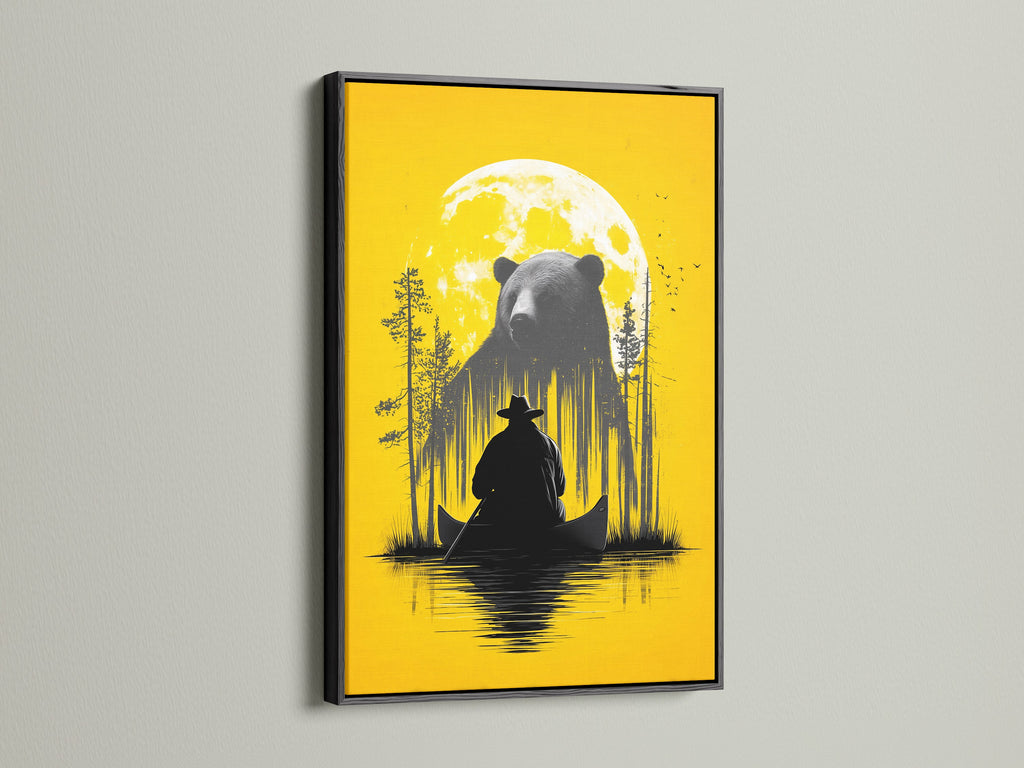 Framed Bear and Canoe artwork is displayed. The frame is a black frame. It is a rustic nature wall art. It shows a bear and a canoe under a yellow moon. Ideal for cabin decor and adventure art lovers. The black frame adds a touch of sophistication. It enhances the contrast of the artwork.