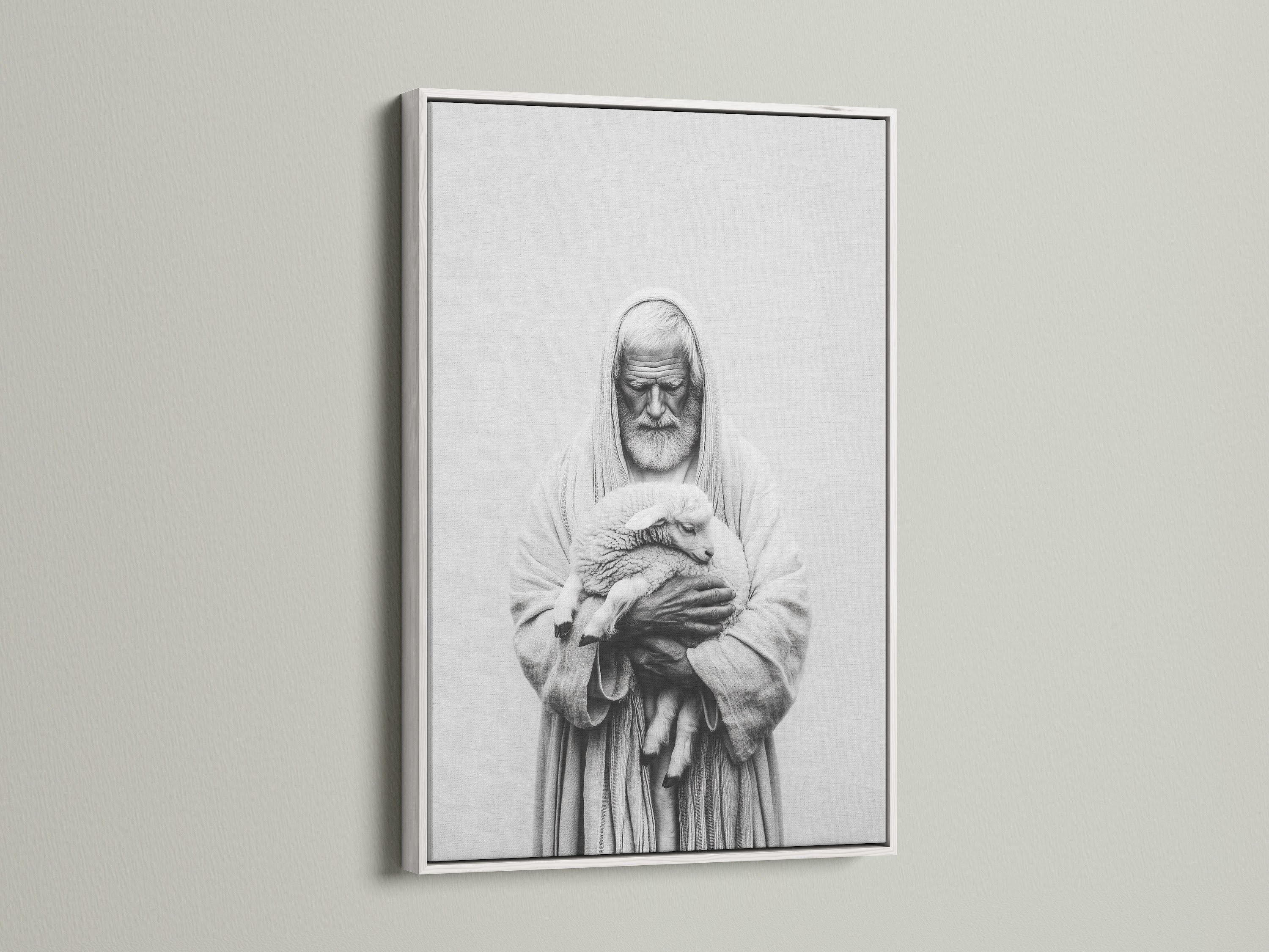 A framed artwork hangs on a light beige wall. The artwork has a white frame. The frame is thin and modern. The art print is a black and white image of a man holding a lamb. This framed art print is perfect for any room.