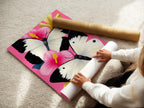 A woman is carefully rolling a fine art poster paper featuring a butterfly canvas print. The artwork showcases pink hibiscus wall art with delicate white butterflies. Perfect for nature artwork botanical prints and girly decor.