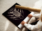 A woman rolling a fine art poster paper featuring Zebra Celestial artwork. This gothic animal wall art features sacred geometry. The fine art poster is perfect for any space. Add spiritual art to your bedroom wall. A unique black art print.