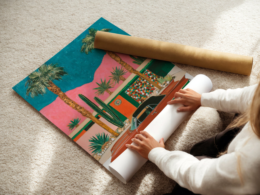 A woman carefully rolls a fine art poster paper print. This retro Palm Springs artwork is ready to be displayed. The vintage car and desert wall art capture a mid-century modern vibe. Perfect for adding a touch of California charm to your home or office decor.