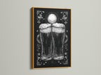 A framed artwork is on display. The art is in a gold frame. The artwork features a monochromatic illustration of two beer glasses. The beer glasses are the focal point. The print adds a touch of elegance to any room. The gold frame brings a touch of luxury.