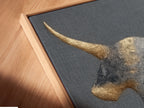 Here is a close-up of a canvas print in a floating frame. The golden bull artwork looks stunning. This modern farmhouse decor is perfect for study rooms. The minimalist art complements any space. Elevate your walls with this unique piece of abstract art. This is ideal for masculine spaces.