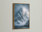 A gold frame enhances a moody landscape art print of snowy mountain peaks. This nature wall art brings a touch of Scandinavian style to your space. It is an ideal fjord art piece.