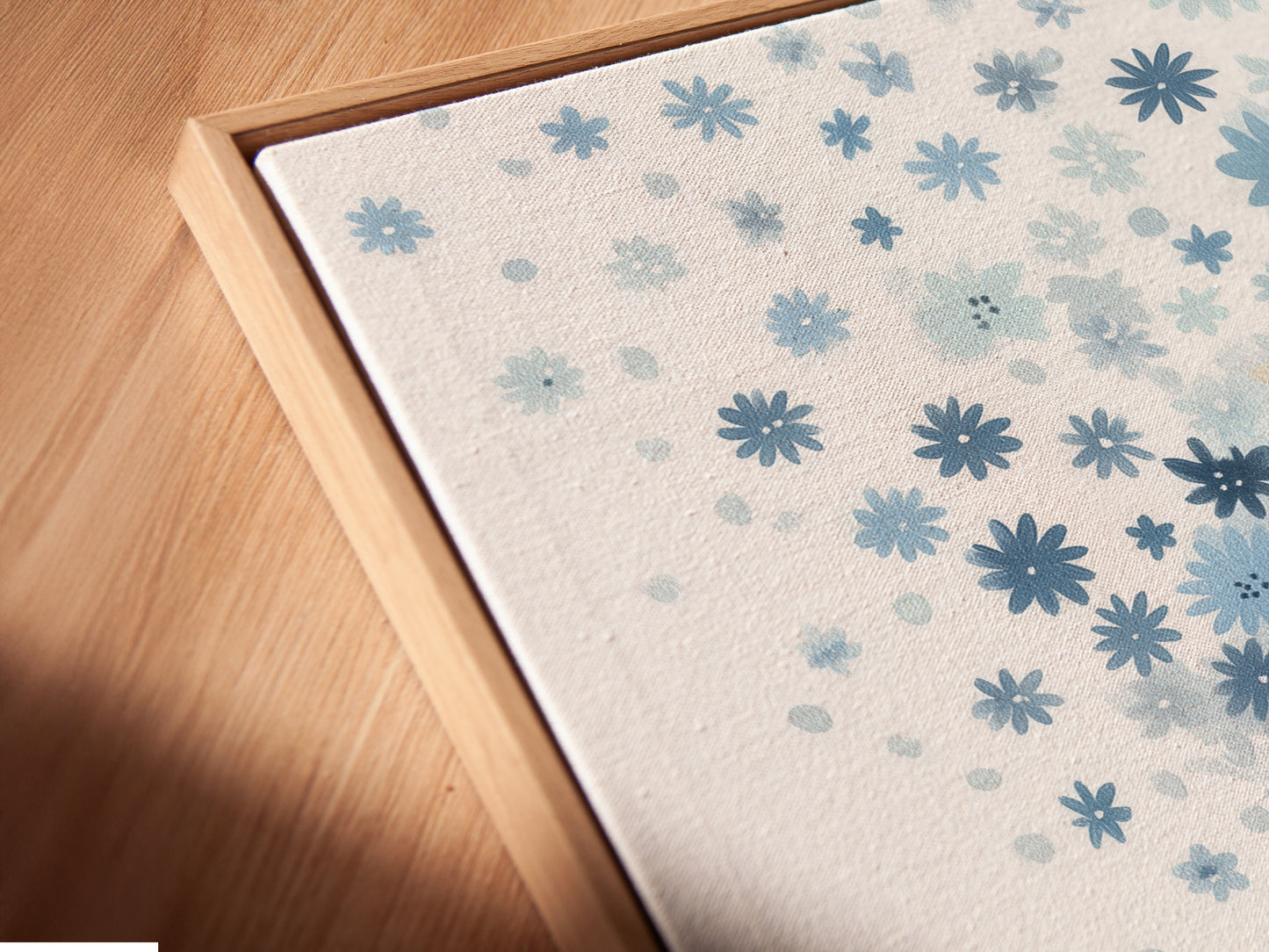 A close-up angled view of a blue floral canvas print in a floating frame. The floating frame gives the artwork a modern and airy feel. The pastel botanical art and whimsical flower tree art create a serene atmosphere. Perfect for any kids room.