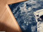 A close-up angled view reveals a canvas print in a floating frame. The astronaut space art is beautifully displayed. This modern art piece is ideal for contemporary minimalist or industrial styles. Elevate your walls with cosmic artwork.