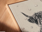 A close-up shot showcases a canvas print of a Highland Cow. The artwork features a black and white image of a cow relaxing in a bathtub filled with bubbles. It is set in a floating frame. Perfect addition of Country Farmhouse style bathroom art or wall decor.