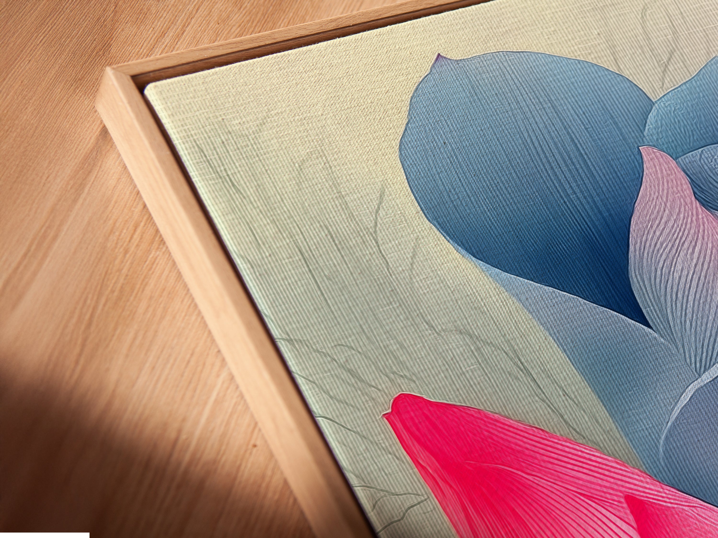 Angled close-up of a pink and blue lotus flower canvas print in a floating frame. Floating frames highlight the artwork's edges creating a gallery-like display. This modern botanical artwork is perfect for bedrooms and living rooms. Elevate your space.