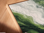 A close-up shows a canvas print in a floating frame. Green abstract art meets modern wall decor. The marble print features emerald and white swirls. This swirl artwork is perfect for contemporary spaces. Ideal for adding a touch of elegance to your home or office. Enhance your walls today.