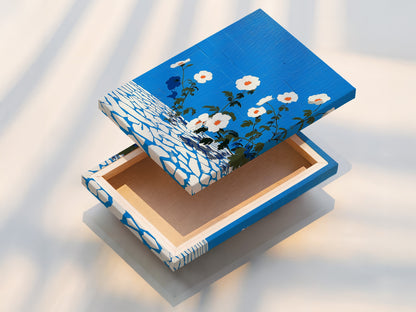 The image shows a stretched canvas print of floral artwork. The azure blue and botanical print create a modern look. This stretched canvas is ready to hang. Enhance your space with this flower artwork.