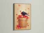 Bird and Apples canvas print with an oak frame. This autumn harvest wall art is perfect for adding a rustic touch to your kitchen. It is a charming addition to any farmhouse-style home. The print features a bird on a bucket filled with red apples. The oak frame enhances its warm and inviting feel.